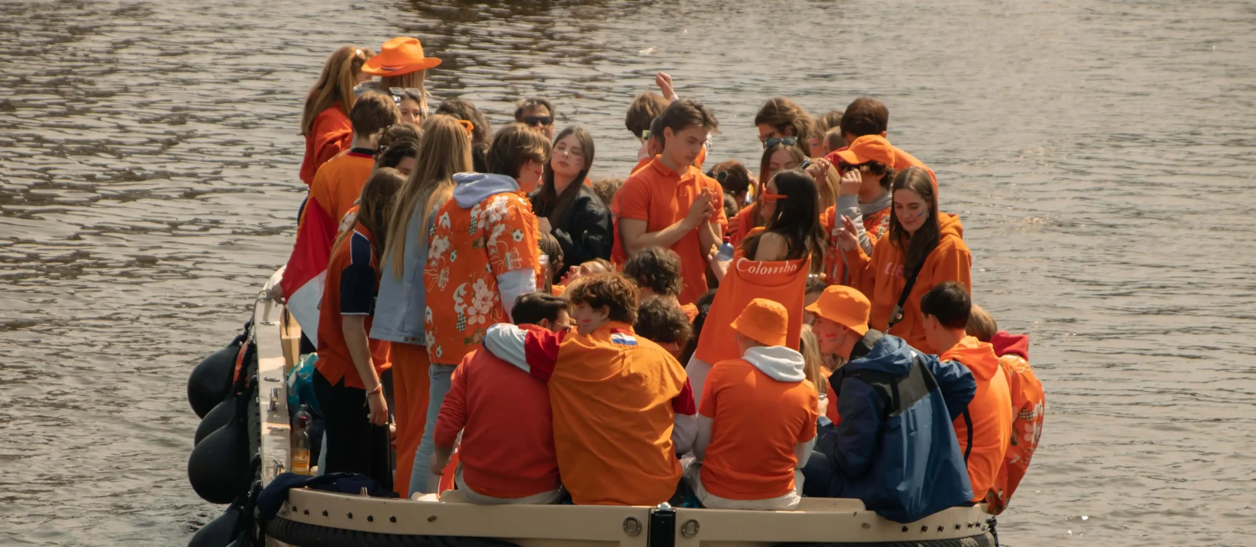 People dressed in orange celebrating King's day on a boat party in the canals of Amsterdam 