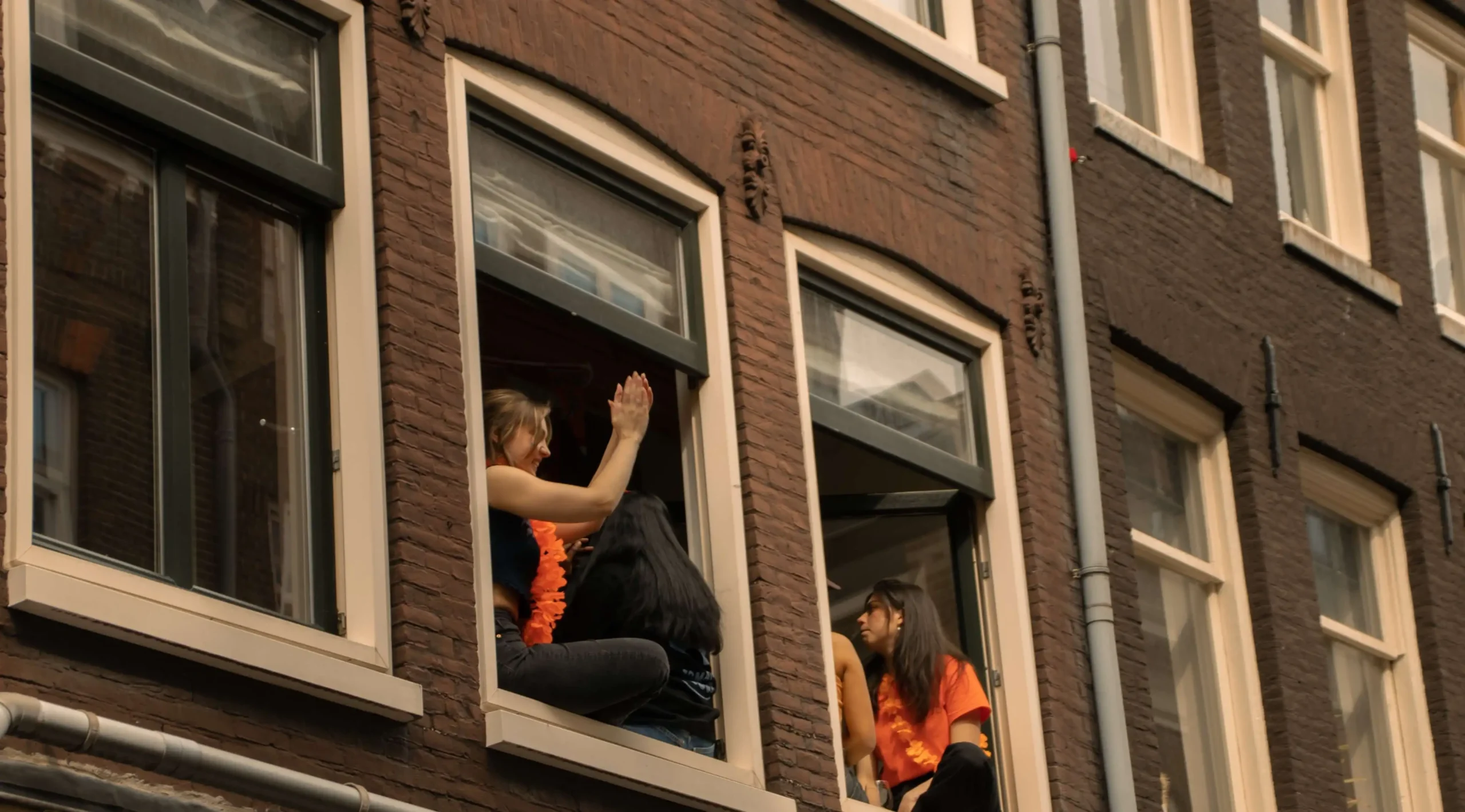 Women enjoying King's day Amsterdam from a view of an Amsterdam canal house window 